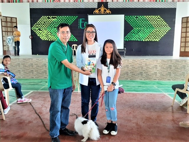 Educators and girl with dog learning about rabies prevention  and pet care, Philippines.